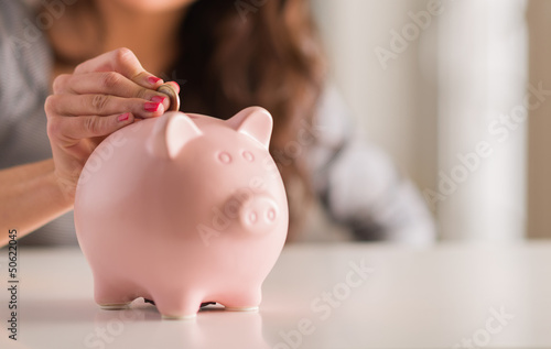 Photo: Woman Putting Coin In Piggy Bank Woman Putting Coin In Piggy Bank