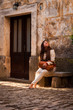 A cute woman sitting on a stone bench in an old mediterranean st