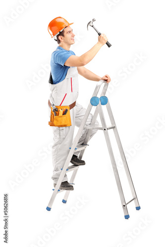Photo: Full length portrait of a repairman on a ladder working with a h Full length portrait of a repairman on a ladder working with a h