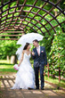 Happy bride and groom goes along the arch