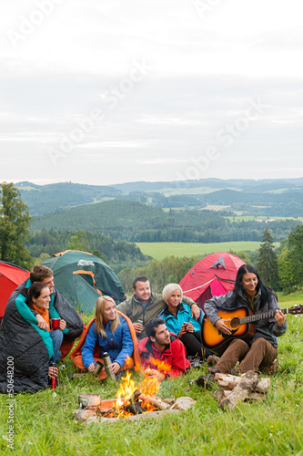 Photo: Camping friends playing guitar beside fire nature Camping friends playing guitar beside fire nature