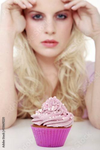 Photo: Junge hübsche Frau mit Cupcake blickt cool Junge hübsche Frau mit Cupcake blickt cool