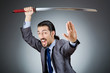 Angry businessman with sword in dark room