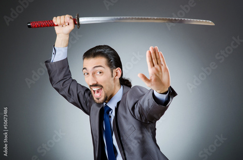 Photo: Angry businessman with sword in dark room Angry businessman with sword in dark room