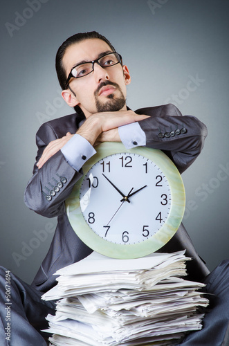 Photo: Man with clock and pile of papers Man with clock and pile of papers