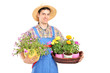 Male gardener with a straw hat holding flower plants