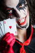 Evil clown with cards in dark room