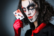 Evil clown with cards in dark room