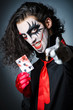 Evil clown with cards in dark room