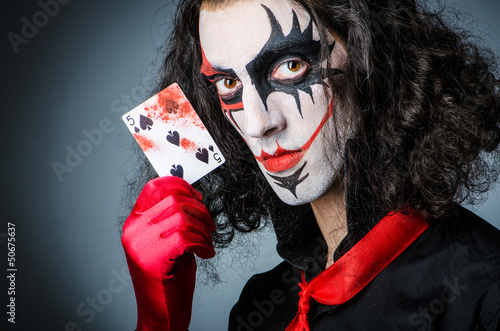 Photo: Evil clown with cards in dark room Evil clown with cards in dark room