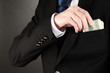 Business man hiding money in pocket on black background