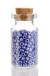 Little bottle full with colorful beads isolated on white