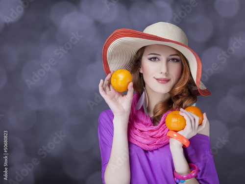 Photo: Beautiful red-haired girl with oranges at bokeh background Beautiful red-haired girl with oranges at bokeh background
