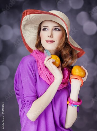 Photo: Beautiful red-haired girl with oranges at bokeh background Beautiful red-haired girl with oranges at bokeh background