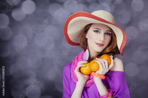 Photo: Beautiful red-haired girl with oranges at bokeh background Beautiful red-haired girl with oranges at bokeh background