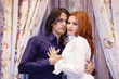 Embracing young couple near curtained window