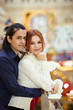Dark-haired man embrace red-haired woman from behind