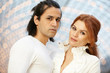 Dark-haired man and red-haired woman stand side by side and look