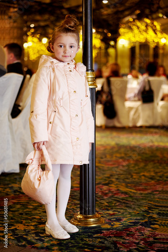 Photo: Girl in light coat stands near to decorative lamp post Girl in light coat stands near to decorative lamp post