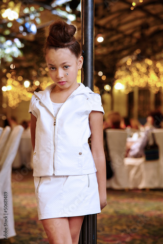 Photo: Girl in white leather suit stands near decorative lamppost Girl in white leather suit stands near decorative lamppost