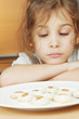 Little girl sits, chin resting on her folded arms and sadly look