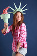Pretty girl in pink shirt with crown and torch represents statue