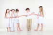 Five strained little children in white clothes draw over rope