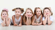 Five cute little children in white clothes lie on floor and look