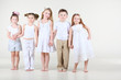 Four cute little girls and one boy in white clothes stands