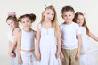 Five smiling children in white clothes stand and look at camera.