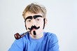 Little boy in blue with pipeful, fake mustache, eyebrows, beard