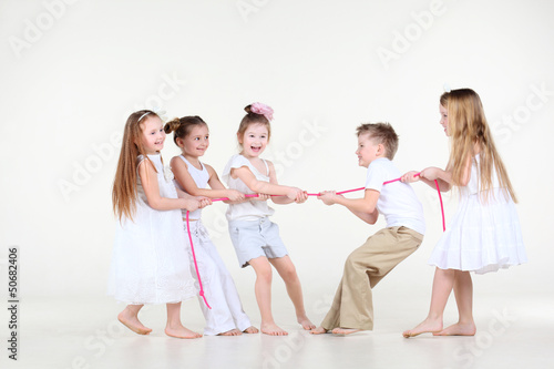 Photo: Five happy little children in white clothes draw over pink rope. Five happy little children in white clothes draw over pink rope.