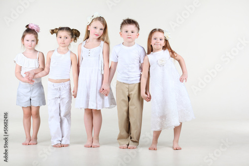 Photo: Four cute little girls and one boy in white clothes stands Four cute little girls and one boy in white clothes stands