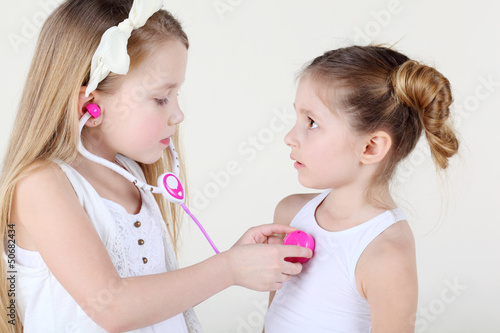 Photo: Little girl listens heartbeat of another frightened girl Little girl listens heartbeat of another frightened girl