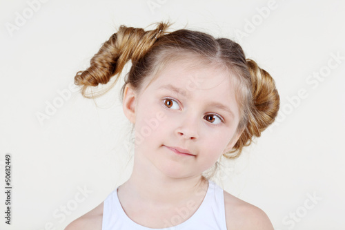 Photo: Little thoughtful girl with funny hairdo in white shirt Little thoughtful girl with funny hairdo in white shirt