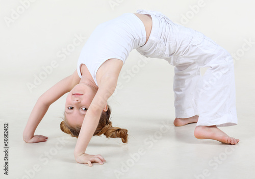 Photo: Little happy girl with funny hairdo in white clothes exercis Little happy girl with funny hairdo in white clothes exercis
