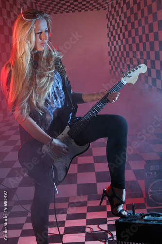 Photo: Beautiful girl holds electric guitar in studio in smoke Beautiful girl holds electric guitar in studio in smoke