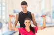 Woman with her personal trainer exercising with weights in gym