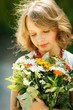 Smiling little girl with bunch of wildflowers standing outdoors