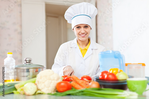 Photo: cook woman in uniform cutting vegetables cook woman in uniform cutting vegetables