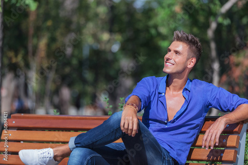 Photo: man on bench looks away man on bench looks away