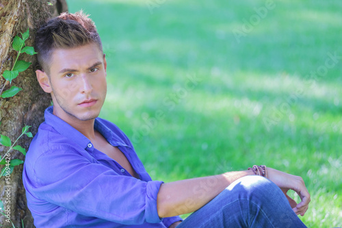 Photo: serious man leaning on tree serious man leaning on tree