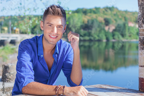 Photo: man at table near lake man at table near lake