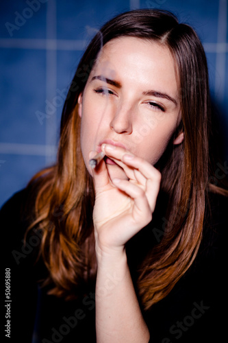Photo: Getting high. Young woman smoking a joint. Selective focus. Getting high. Young woman smoking a joint. Selective focus.