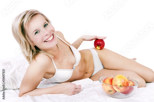Photo: Bed of a beautiful blond woman holding apple. Bed of a beautiful blond woman holding apple.