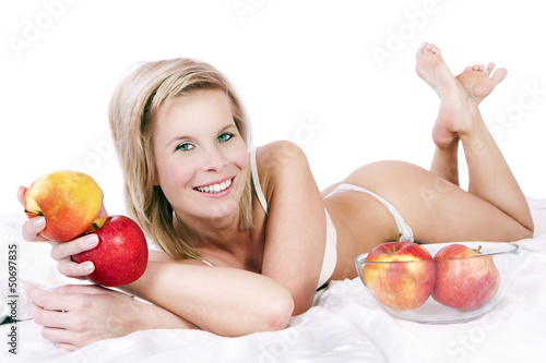 Photo: Cheerful girl in bed surrounded by apples. Cheerful girl in bed surrounded by apples.
