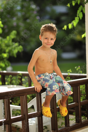 Photo: wonderful emotional little boy sitting on a fence in the open ai wonderful emotional little boy sitting on a fence in the open ai