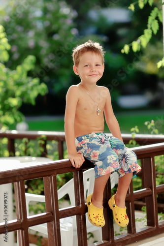 Photo: wonderful emotional little boy sitting on a fence in the open ai wonderful emotional little boy sitting on a fence in the open ai