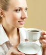 Photo: Young woman drinking coffee or tea, at home Young woman drinking coffee or tea, at home