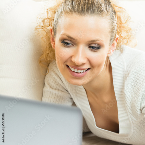Photo: Cheerful woman with laptop, at home Cheerful woman with laptop, at home